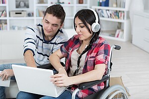 a woman in a wheelchair with friend helping her